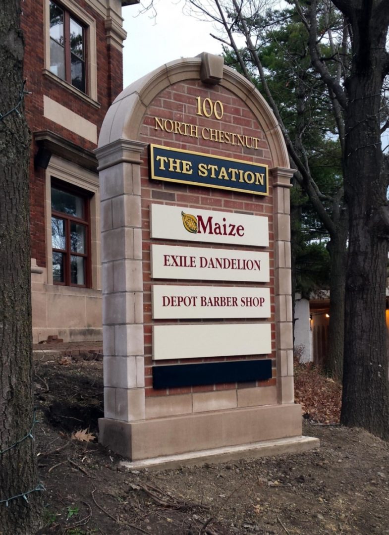 Brick and limestone monument sign with dimensional, metal letters and tenant panels.